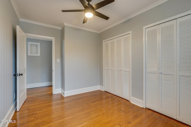 unfurnished bedroom with ceiling fan, light hardwood / wood-style floors, crown molding, and two closets