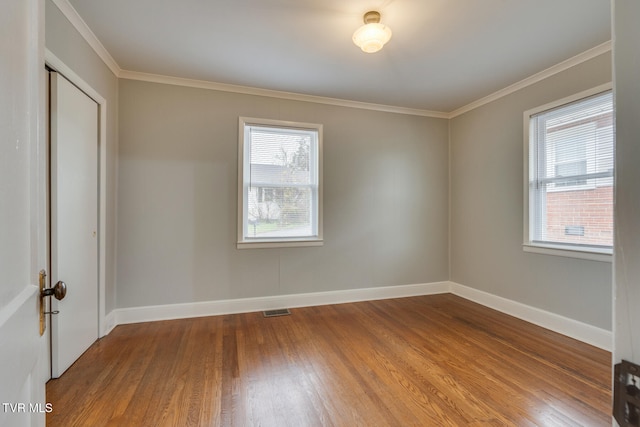 spare room with hardwood / wood-style floors, a healthy amount of sunlight, and ornamental molding