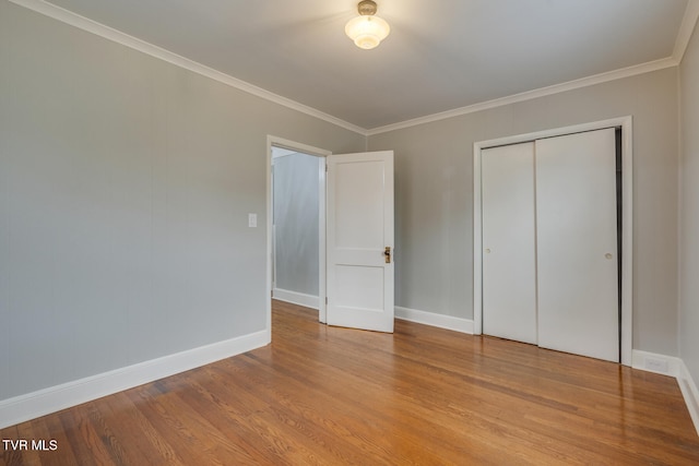 unfurnished bedroom featuring wood-type flooring, a closet, and ornamental molding