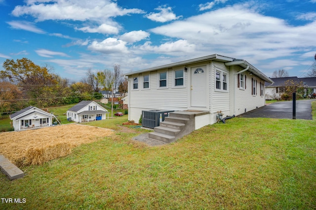 view of front of home with central AC unit and a front lawn