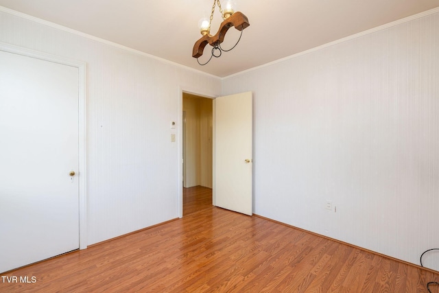 unfurnished room with light hardwood / wood-style flooring, a notable chandelier, and crown molding