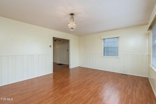 spare room with hardwood / wood-style floors and a notable chandelier