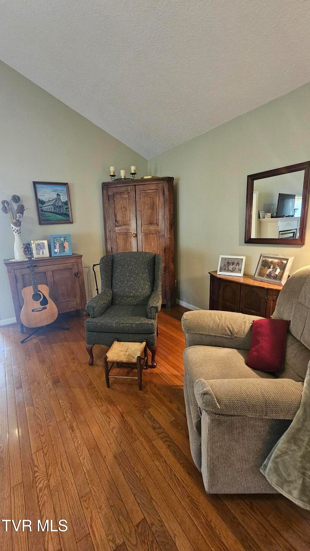 living room with hardwood / wood-style floors, a textured ceiling, and lofted ceiling