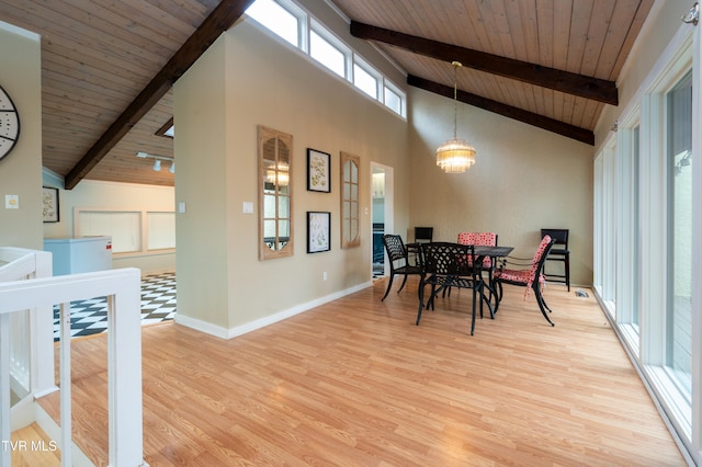 dining space featuring beamed ceiling, light wood-type flooring, an inviting chandelier, and wood ceiling