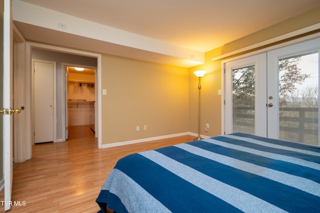 bedroom with a spacious closet, french doors, hardwood / wood-style floors, access to outside, and a closet