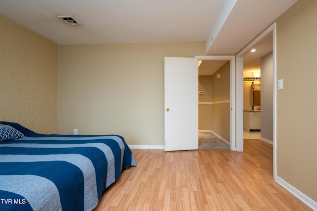 bedroom featuring light hardwood / wood-style floors and a textured ceiling