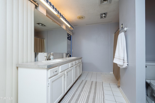 bathroom with tile patterned flooring, vanity, a textured ceiling, and toilet