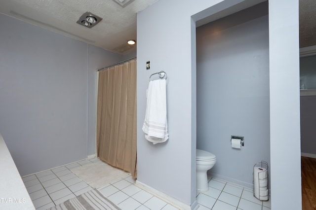 bathroom with tile patterned flooring, a textured ceiling, and toilet