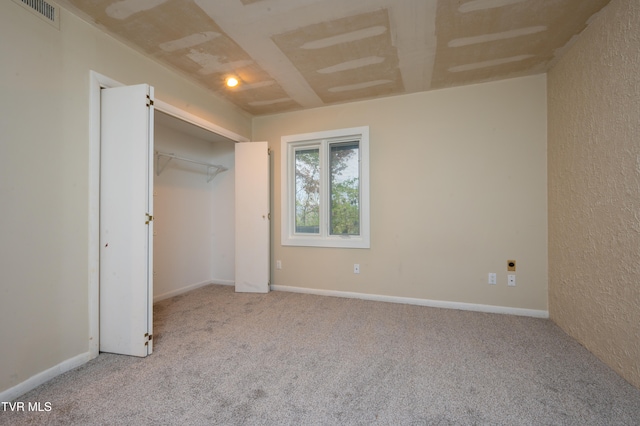 unfurnished bedroom with light carpet and a closet