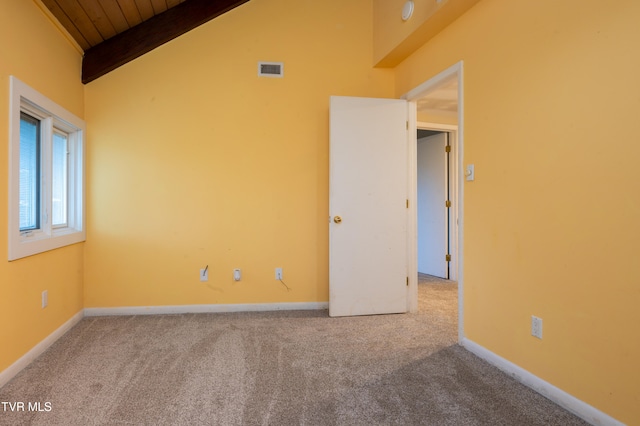 carpeted empty room with vaulted ceiling with beams and wooden ceiling