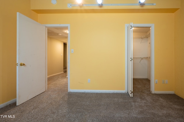 unfurnished bedroom with carpet flooring, a walk in closet, and a closet