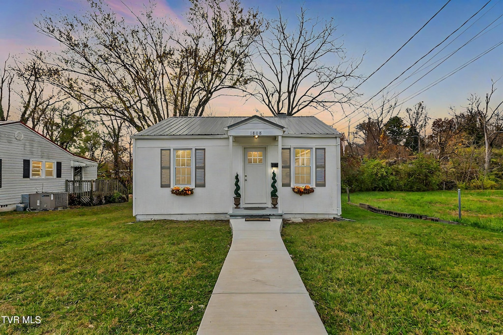 view of front facade featuring central AC unit and a lawn