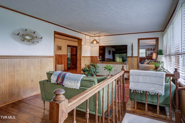 living room with wood walls, wood-type flooring, and crown molding