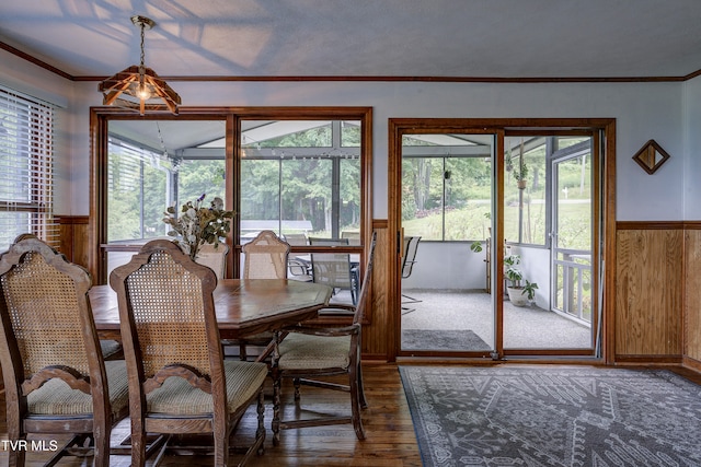 dining area featuring wooden walls, dark hardwood / wood-style floors, and ornamental molding