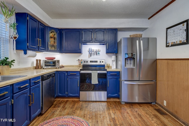 kitchen with blue cabinetry, stainless steel appliances, and hardwood / wood-style flooring