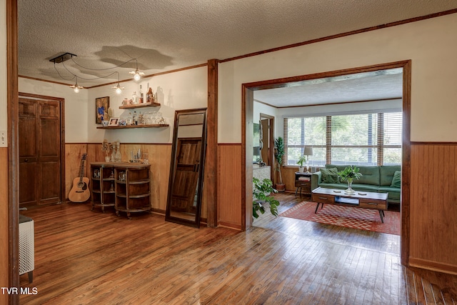 interior space with hardwood / wood-style floors, ornamental molding, and a textured ceiling