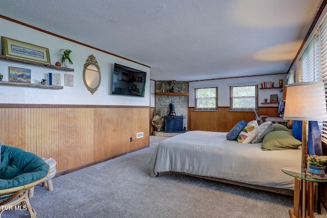 bedroom featuring a textured ceiling, light colored carpet, a wood stove, and wood walls