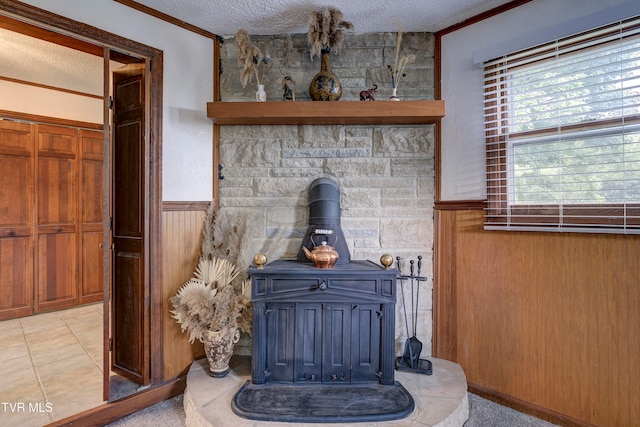 interior details with a wood stove, wood walls, a textured ceiling, and ornamental molding