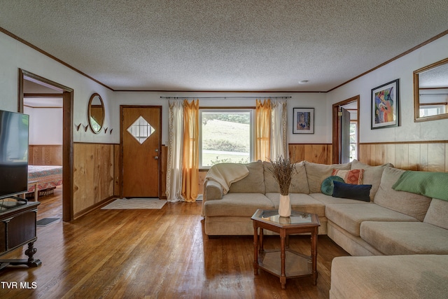 living room with crown molding, hardwood / wood-style floors, a textured ceiling, and wooden walls