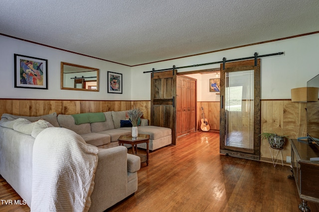 living room featuring a barn door, crown molding, hardwood / wood-style floors, and a textured ceiling