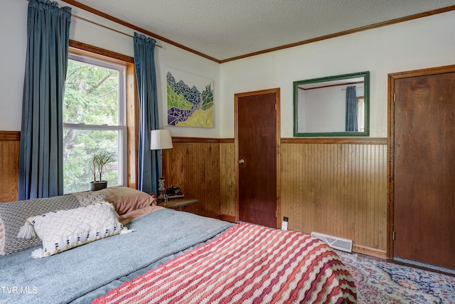 bedroom with wood walls, a textured ceiling, and ornamental molding