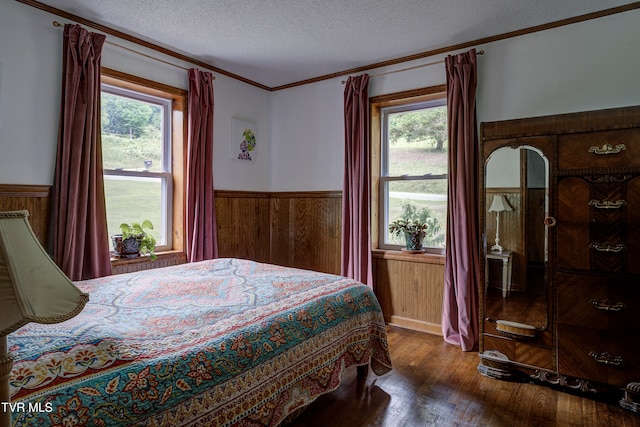 bedroom featuring multiple windows, crown molding, dark wood-type flooring, and a textured ceiling