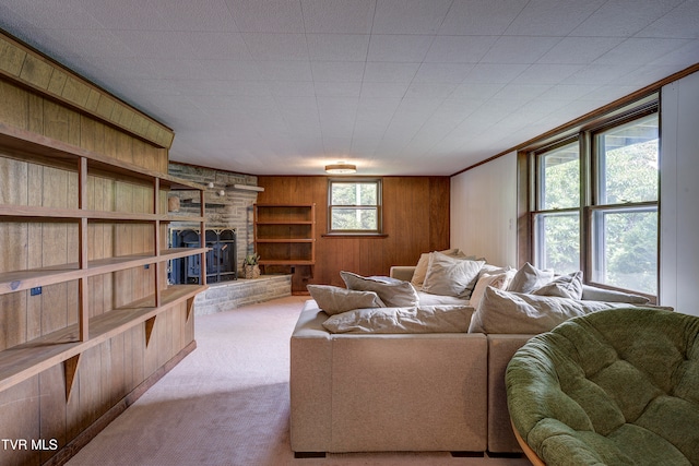 living room with a fireplace, wood walls, crown molding, and light carpet