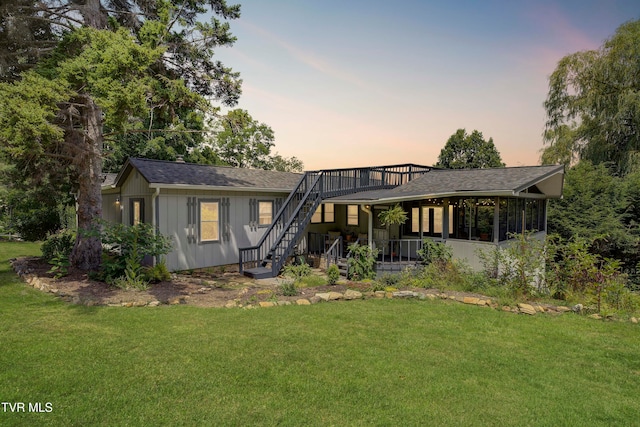 back house at dusk featuring a lawn