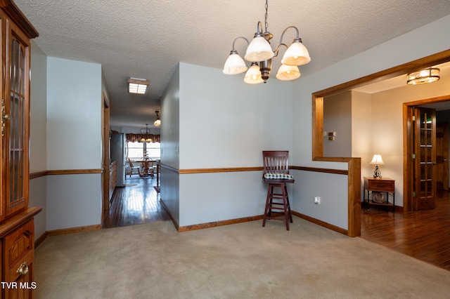 interior space with hardwood / wood-style floors, a textured ceiling, and a notable chandelier