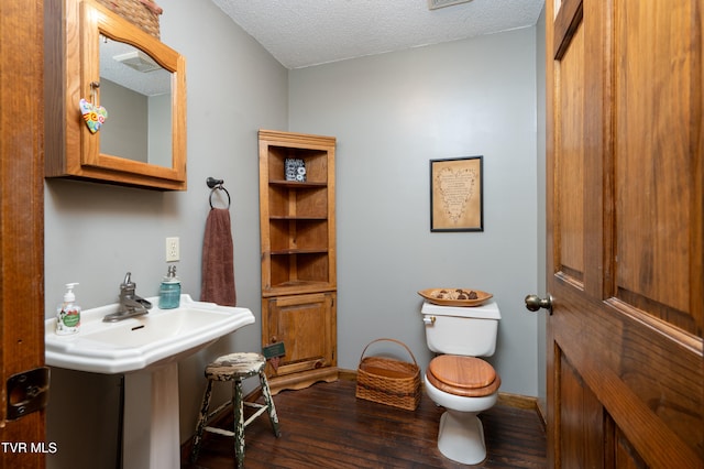 bathroom with toilet, wood-type flooring, and a textured ceiling