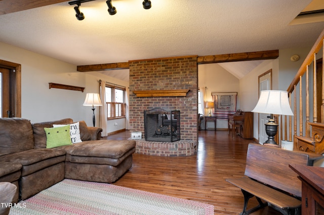 living room with dark hardwood / wood-style flooring, lofted ceiling with beams, a textured ceiling, and a brick fireplace