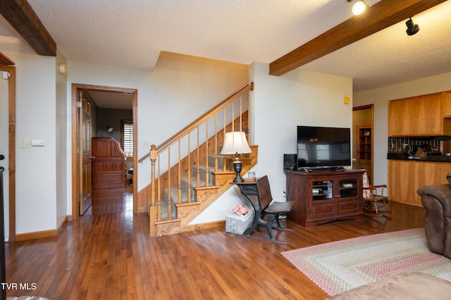 living room featuring a textured ceiling, beamed ceiling, and dark hardwood / wood-style floors