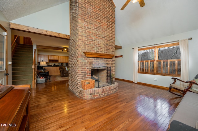 unfurnished living room with high vaulted ceiling, ceiling fan, a textured ceiling, a fireplace, and wood-type flooring