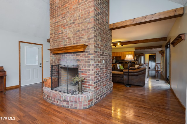 living room featuring hardwood / wood-style flooring, lofted ceiling with beams, and a brick fireplace