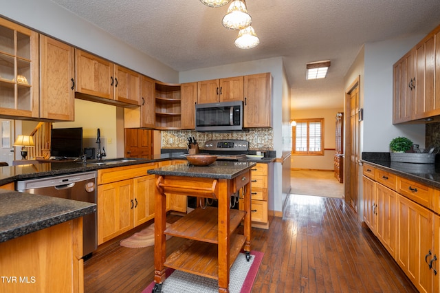 kitchen with sink, stainless steel appliances, dark hardwood / wood-style floors, pendant lighting, and a textured ceiling