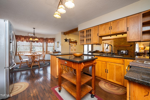 kitchen featuring a textured ceiling, stainless steel appliances, sink, decorative light fixtures, and dark hardwood / wood-style floors