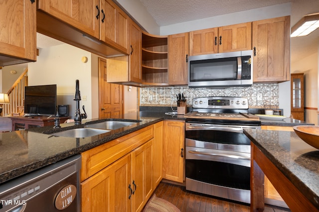 kitchen with dark stone counters, dark hardwood / wood-style floors, a textured ceiling, tasteful backsplash, and stainless steel appliances