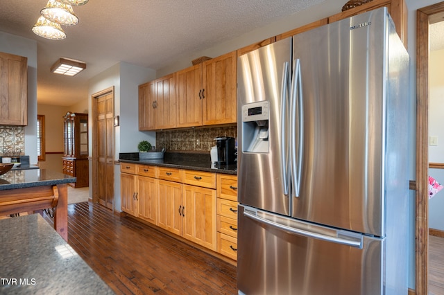 kitchen featuring a textured ceiling, backsplash, stainless steel fridge, and dark hardwood / wood-style floors