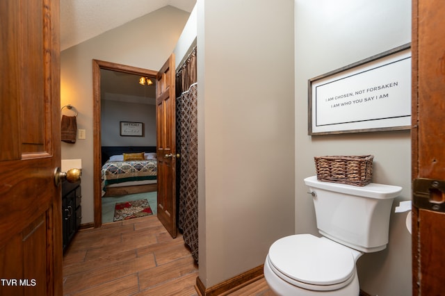 bathroom featuring a textured ceiling, toilet, lofted ceiling, and hardwood / wood-style flooring