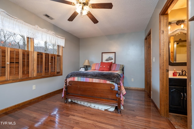 bedroom featuring connected bathroom, ceiling fan, sink, dark hardwood / wood-style flooring, and a textured ceiling