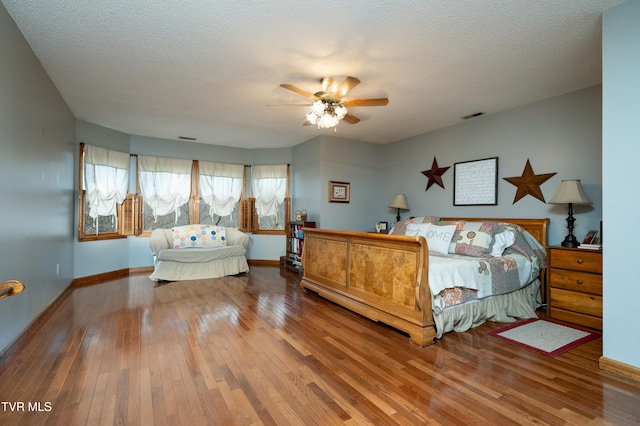 bedroom with hardwood / wood-style flooring, ceiling fan, and a textured ceiling