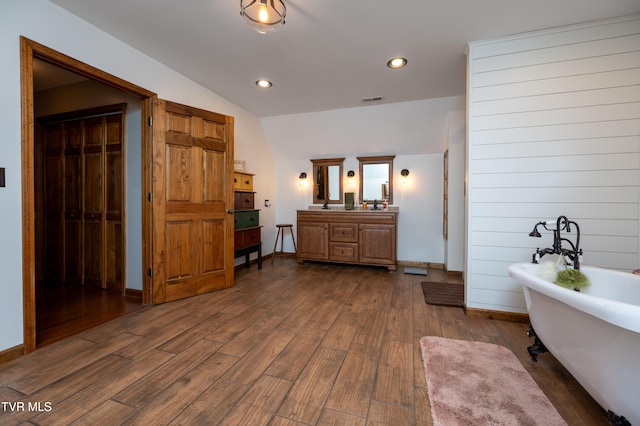 bathroom featuring hardwood / wood-style flooring, vanity, a bathing tub, and lofted ceiling