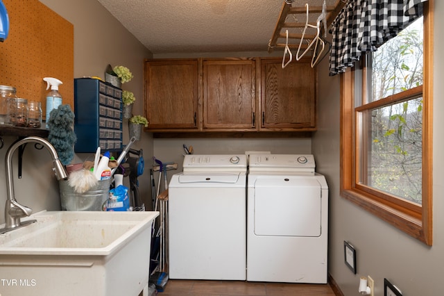 washroom with washing machine and dryer, a wealth of natural light, cabinets, and a textured ceiling