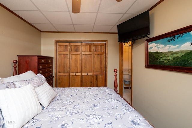 bedroom featuring a drop ceiling, a closet, ceiling fan, and crown molding