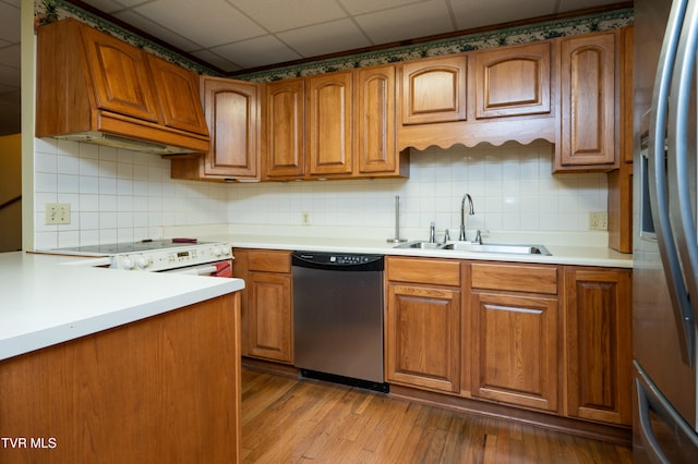 kitchen featuring a drop ceiling, backsplash, sink, appliances with stainless steel finishes, and light hardwood / wood-style floors