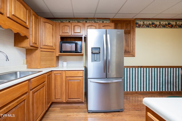 kitchen featuring black microwave, stainless steel fridge, sink, and a drop ceiling