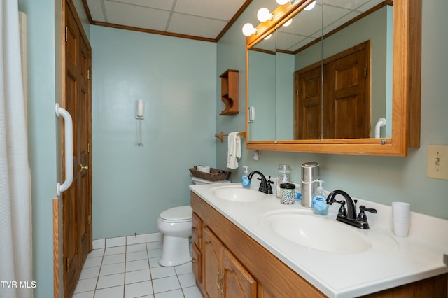 bathroom featuring a paneled ceiling, vanity, tile patterned floors, toilet, and ornamental molding