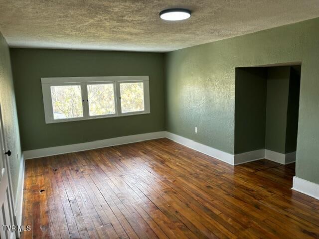 spare room featuring dark hardwood / wood-style flooring and a textured ceiling