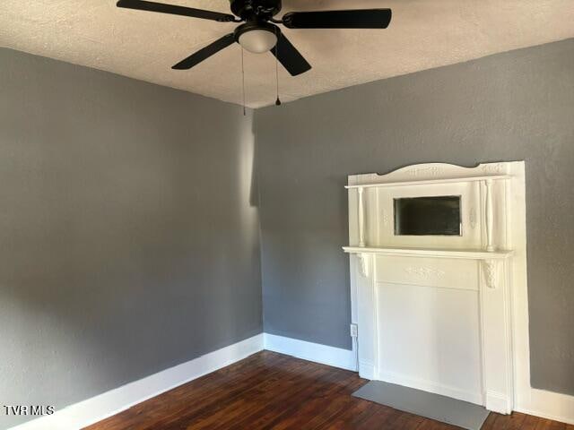 empty room featuring a textured ceiling, ceiling fan, and dark wood-type flooring