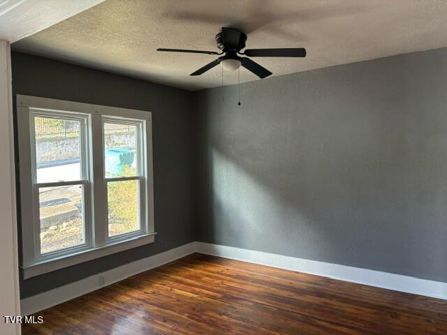 empty room featuring ceiling fan, dark hardwood / wood-style flooring, and a textured ceiling